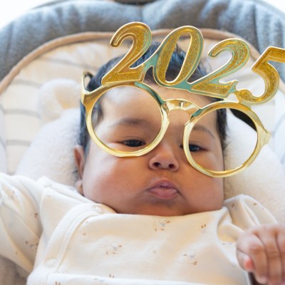 funny portrait of cute dancing baby celebrating with new year 2025 glasses. happy new year 2025 greeting. funny real photo postcard. copy space