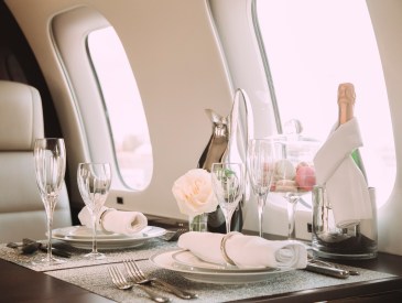 Interior shot of private jet with fancy place settings, flowers, and champagne