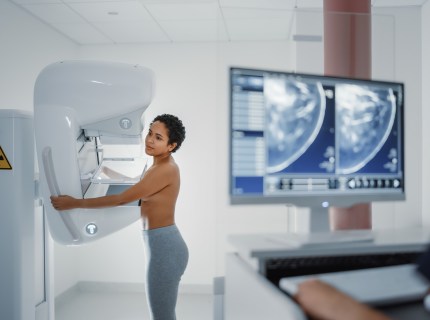 Computer Screen in Hospital Radiology Room: Beautiful Multiethnic Young Woman Standing Topless Undergoing Mammography Screening Procedure. Screen Showing the Mammogram Scans of Dense Breast Tissues.