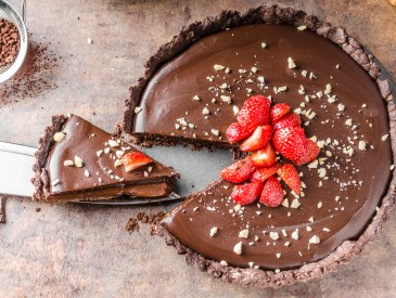 Delicious caramel chocolate tart, topped with nuts and strawberries