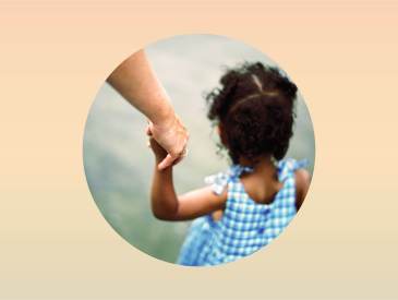 Black child holding white adult hand