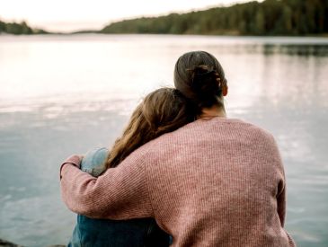 Mom hugging daughter on lakefront