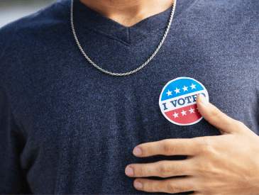 Young mean wearing a blue t-shirt with an 'I Voted' sticker.